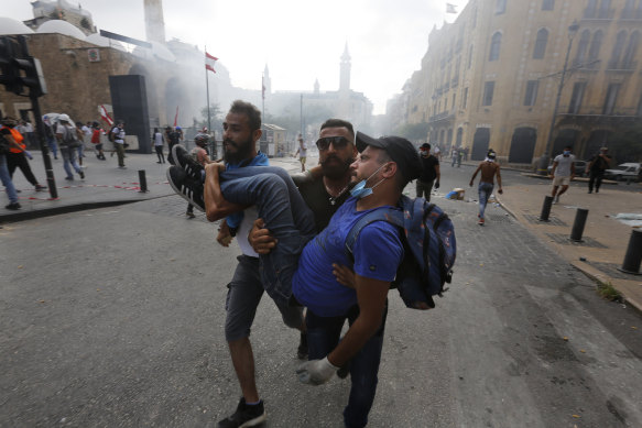 Protesters carry a wounded man during demonstrations on August 8, in Beirut, Lebanon. 