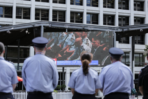 Police, other emergency service personnel and members of the public gather in Brisbane’s King George Square to watch the memorial.