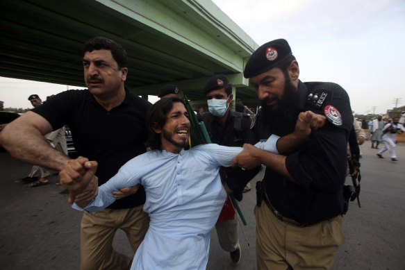 Police officers detain a supporter of Imran Khan in Peshawar, Pakistan on Saturday.