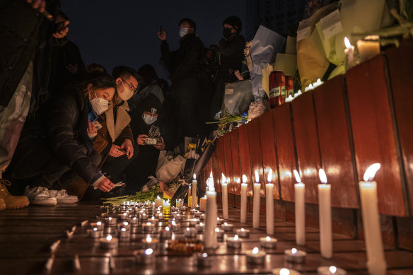 Protesters light candles and leave cigarettes at a memorial during a protest against China’s COVID-zero policies. 