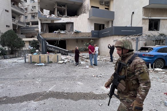 A Lebanese soldier passes in front of a damaged hotel that was hit by an Israeli airstrike in Hazmieh, east of Beirut. 
