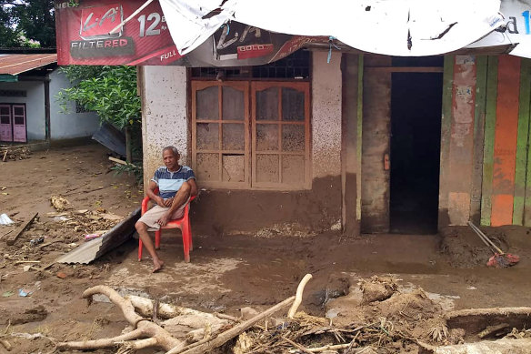 A man sits among flood debris in front of his home in the village of Waiwerang, on Adonara Island, eastern Indonesia.