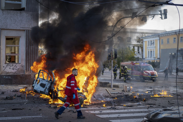 A medical worker runs past a burning car after a Russian attack in Kyiv, Ukraine.