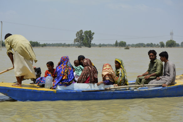In Pakistan in August, displaced people travel floodwaters that followed an extreme monsoon season.