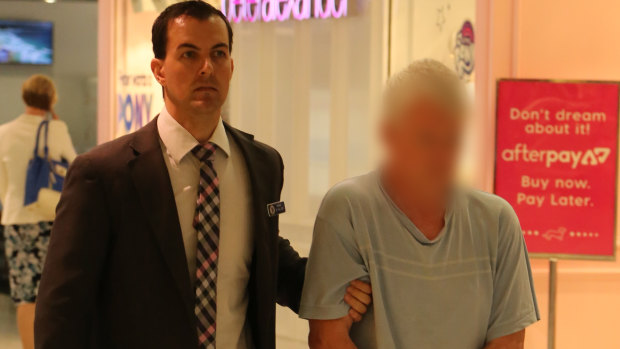 A 67-year-old man is escorted through Sydney Airport, after he was extradited from Queensland on historic sexual abuse charges.