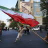 Demonstrators wave a huge Iranian flag backdropped by a building emblazoned with anti-Israeli messages, in Tehran, Iran, on Monday.