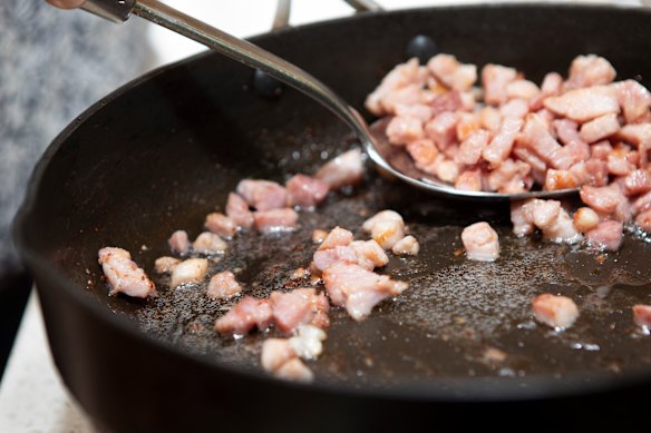 Fry lardons, small “sticks” of cured pork, in a pan to render the fat.
