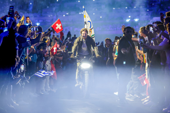 Tom Cruise rides the Olympic flag through the closing ceremony. 