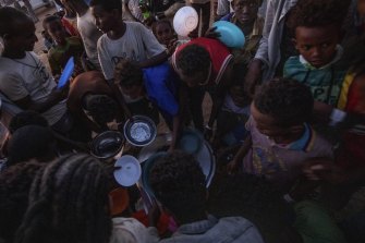 Tigray men who fled the conflict in Ethiopia's Tigray region, receive cooked rice at Umm Rakouba refugee camp in Qadarif, eastern Sudan.