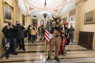 Supporters of President Donald Trump, including Jake Angeli the "Q Shaman" from QAnon, make a stand outside the Senate chamber inside the Capitol.