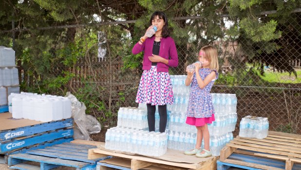 Maria Evans, niece of Jenn Evans, and Matilda Seath-Robinson with pallets of bottled water in Uralla.
