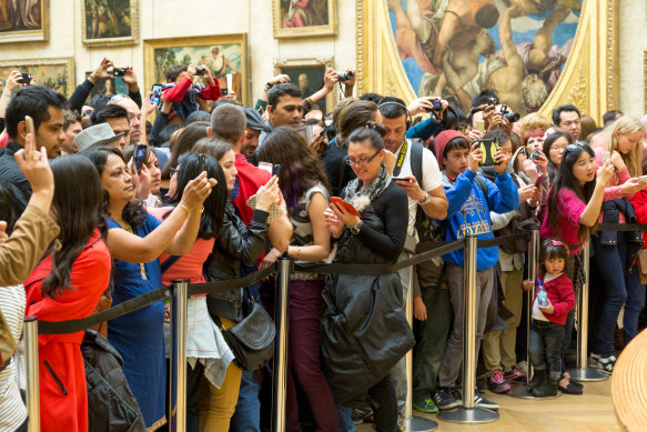 Visitors admire the Mona Lisa from behind a security cordon.