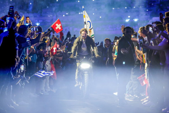 Tom Cruise rides the Olympic flag through the closing ceremony.