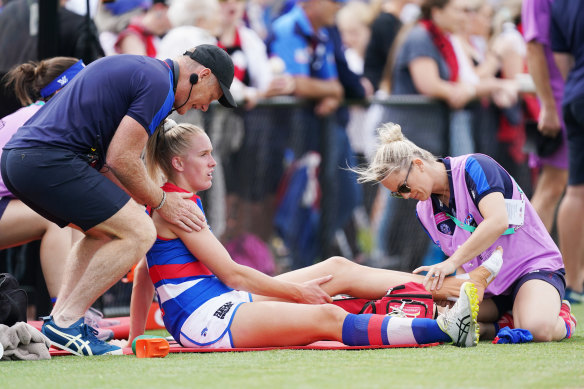 Dogs coach Nathan Burke takes a moment with the injured Celine Moody.