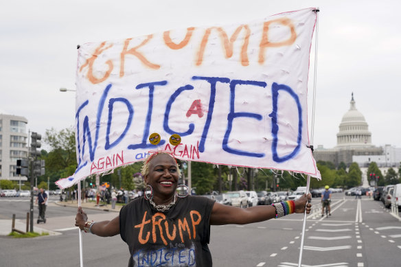 The US Capitol is seen in the distance as Nadine Seiler holds a banner outside the courthouse.