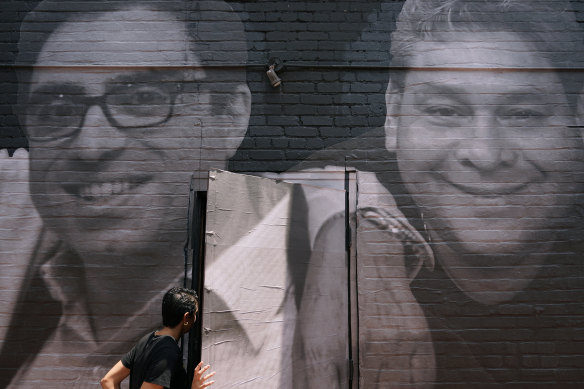 A woman steps through a door that is covered by a mural depicting American hostages in Washington.  Siamak Namazi is on the left. At right is Jose Angel Pereira, an American held in Venezuela.