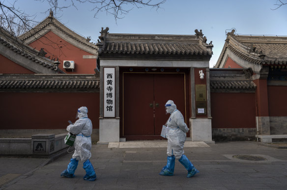 Epidemic control workers wear PPE as they walk by the Huangsi Temple in Beijing.