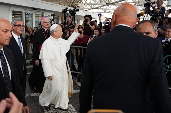 Pope Leo waves to the crowd as he leaves the hospital on Saturday.