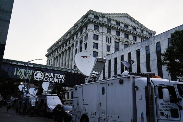Media vehicles stage outside the Fulton County Courthouse.