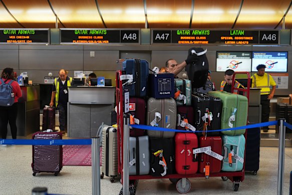 Workers handle luggage at the Qatar Airways ticketing area at the international airport in Los Angeles, Friday.