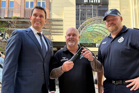 Police Minister Dan Purdie, Brett Beasley and Gold Coast Sergeant Mick Chalmers demonstrate a wand device.