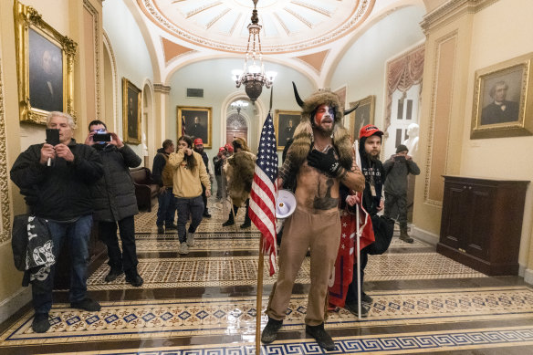 Supporters of President Donald Trump, including Jake Angeli the "Q Shaman" from QAnon, make a stand outside the Senate chamber inside the Capitol.