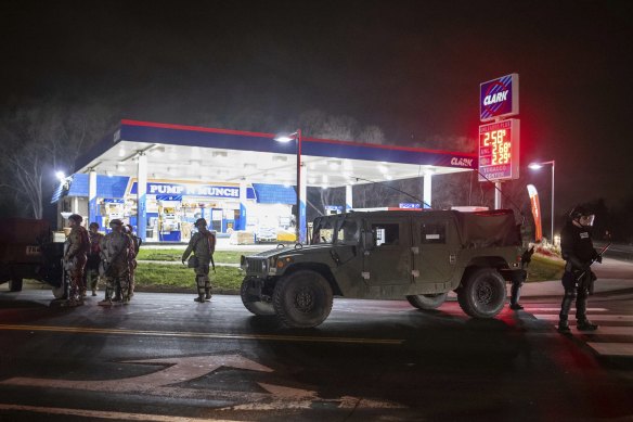 Members of the National Guard stand watch as protesters leave the Brooklyn Centre Police station on Sunday.