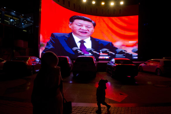 A child walks past a large screen showing Chinese President Xi Jinping near a carpark in Kashgar, western China.