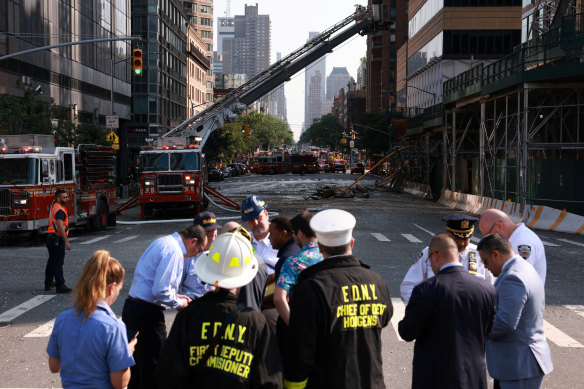 Members of New York City’s fire department and others gather after a construction crane caught fire on a high-rise building in Manhattan.