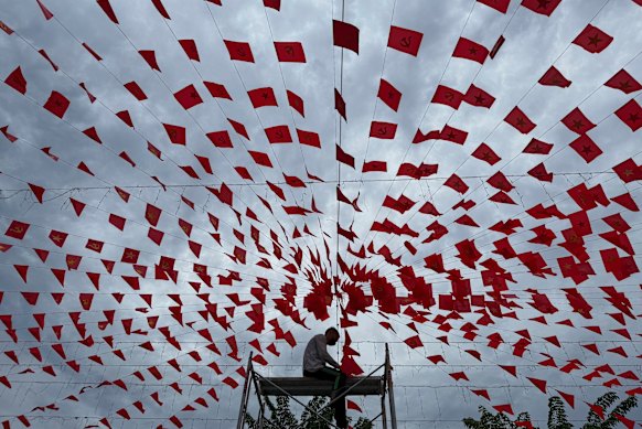 A man hangs up flags in Hanoi in preparation for Vietnam’s national day under a cloudy sky caused by Typhoon Kajiki on Monday.