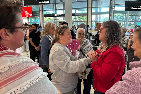 La activista de la flotilla Helen O'Sullivan (centro) llega a Brisbane el lunes por la mañana y es recibida por unos 20 familiares y amigos, incluido Liam Parry (izquierda), la primera persona acusada en virtud de las nuevas leyes sobre incitación al odio de Queensland. 
