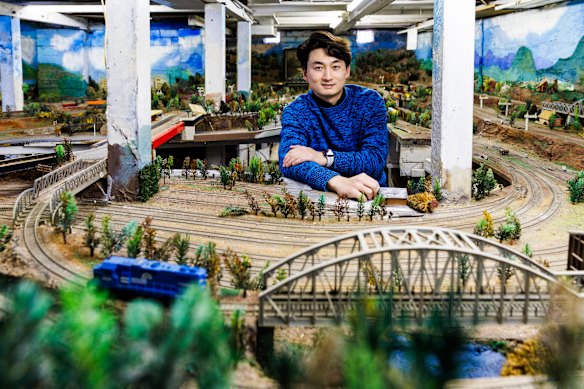 Daniel Xu with the full train set underneath the house he bought.