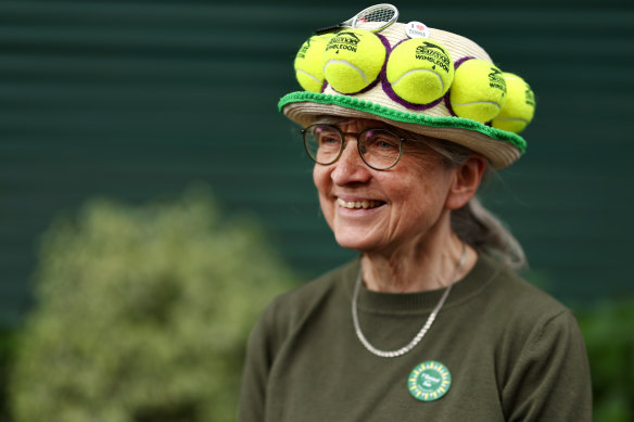 A spectator wears a hat adorned with tennis balls and tennis theme decorations.