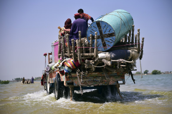 Victims of flooding from monsoon rains carry belongings salvaged from their flooded home in Sehwan, Sindh province, Pakistan.