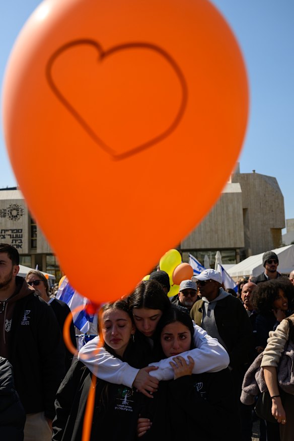 A crowd watches a live feed from a funeral for members of the Bibas family in Tel Aviv.