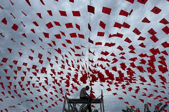 A man hangs up strings of flags to prepare to celebrate Vietnam’s national day under a cloudy sky caused by Typhoon Kajiki in Hanoi.
