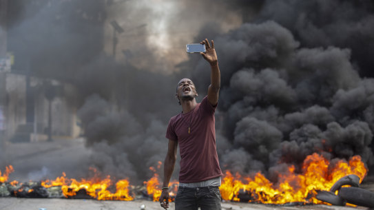 A protester takes a selfie at a burning barricade in Port-au-Prince, Haiti, on Monday.