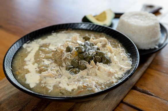 Ajiaco santafereno, a chicken and potato soup garnished with cream and capers, is served with rice and avocado.