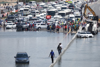 People walk along an flooded highway on April 18 in Dubai.
