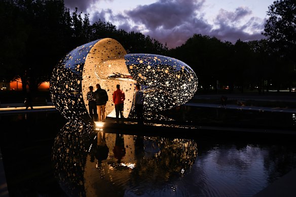 Visitors viewing Lindy Lee’s Ouroboros at night.