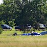 Part of the wreckage of a plane crash is covered with a blue tarp.