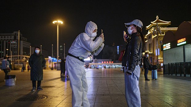 A Chinese man takes a photo of a traveller's document as they arrive at Beijing Railway Station on Friday.