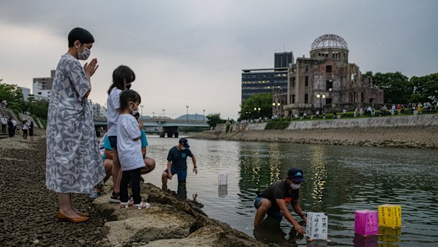 A family prays as paper lanterns are floated on the Tenma River to mark the 75th anniversary of the Hiroshima bombing.