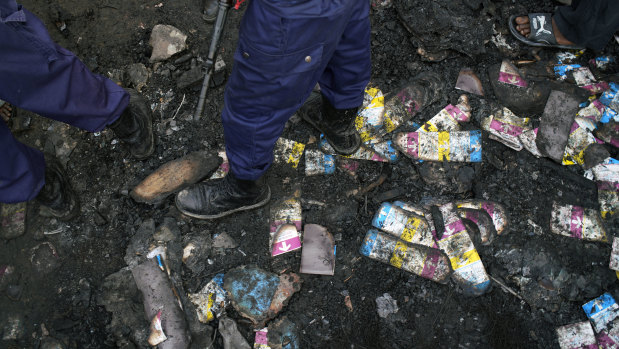 Police stand on burned ballots at the Les Anges primary school in Kinshasa. Voting was delayed when angry voters burned six voting machines angered that the registrations lists had not arrived.