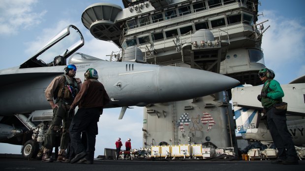 A pilot speaks to a crew member by an F/A-18 fighter jet on the deck of the USS Abraham Lincoln aircraft carrier in the Arabian Sea. Donald Trump has threatened Iran with 'obliteration'.