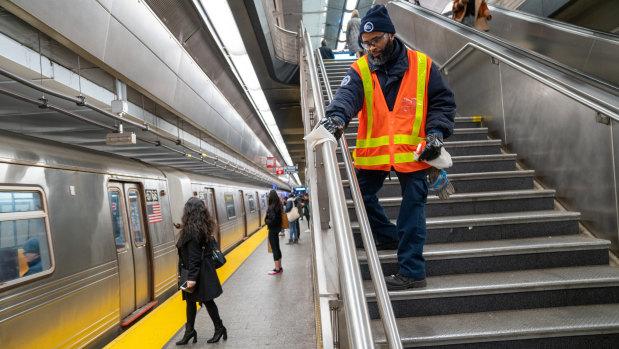 A Metropolitan Transportation Authority worker sprays disinfectant and wipes a railing at the 86th subway station in New York, US. 