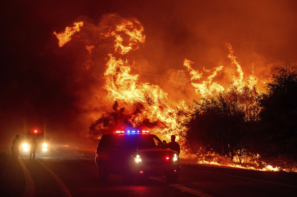 Flames lick above vehicles on Highway 162 as the Bear Fire burns in Oroville, California, on Wednesday.