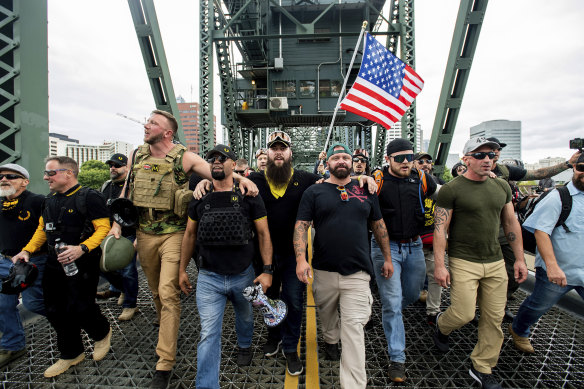 Members of the Proud Boys and other right-wing demonstrators march across the Hawthorne Bridge in Portland, Oregon. The group includes organiser Joe Biggs, in green hat, and Proud Boys chairman Enrique Tarrio, holding a megaphone. 