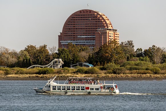 A river cruise takes Chinese tourists past the Sun building and waterslide park in the North Korean city of Sinuiju.