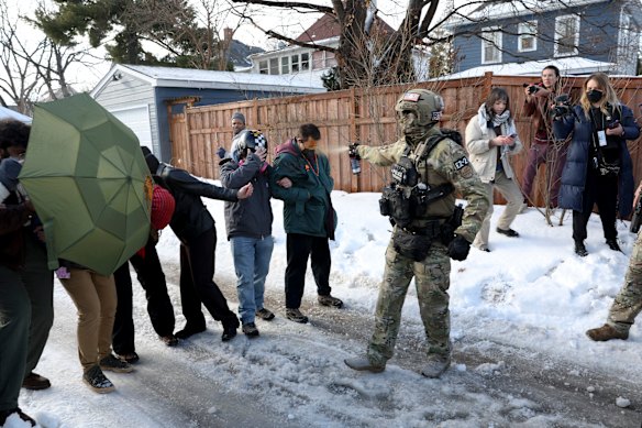 Um agente federal pulveriza um manifestante com um agente químico no local de um tiroteio em Minneapolis.